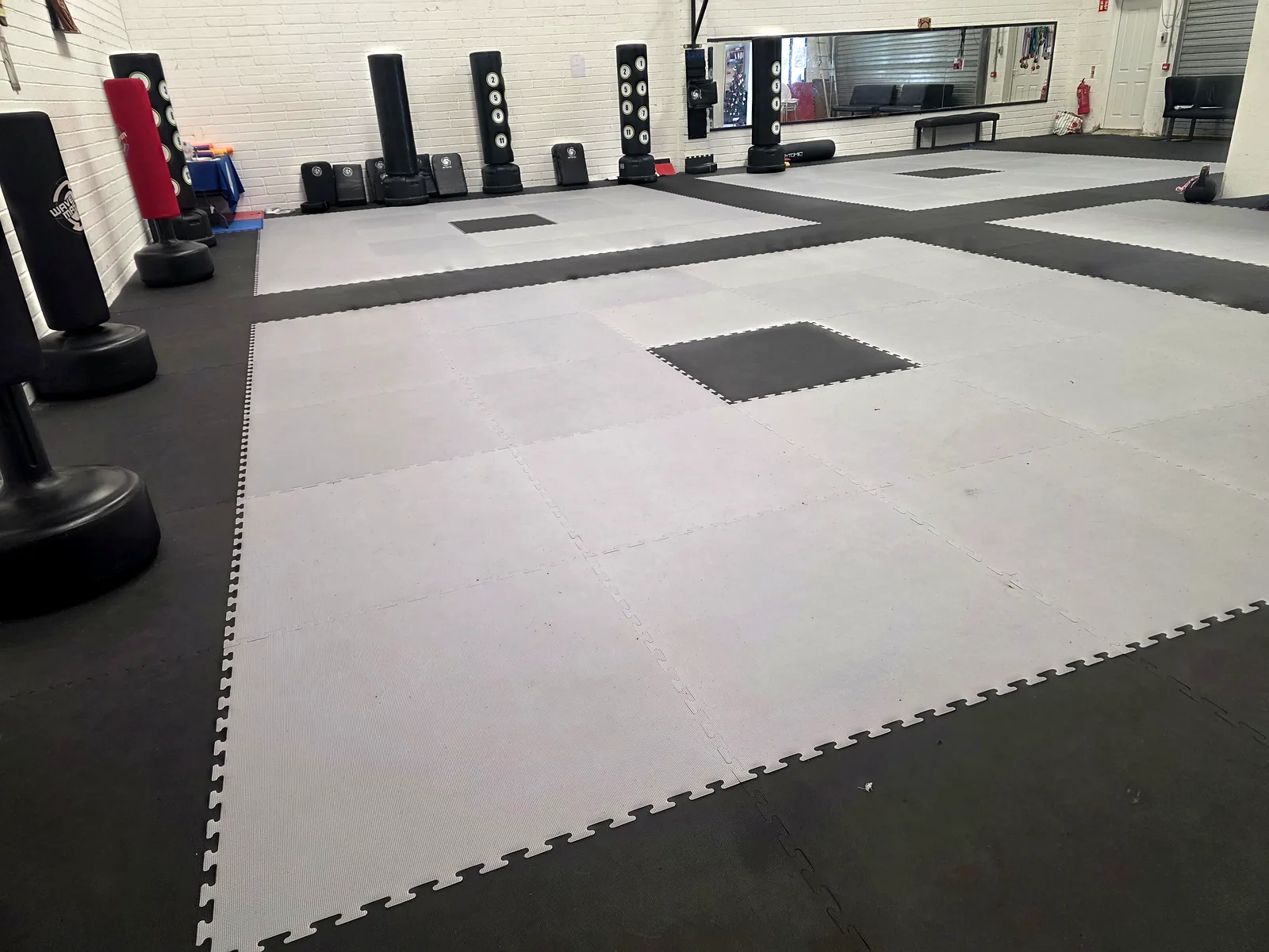 Wide view of the grey and black interlocking mats and kick bags along the wall at the Gorey Taekwon-Do venue