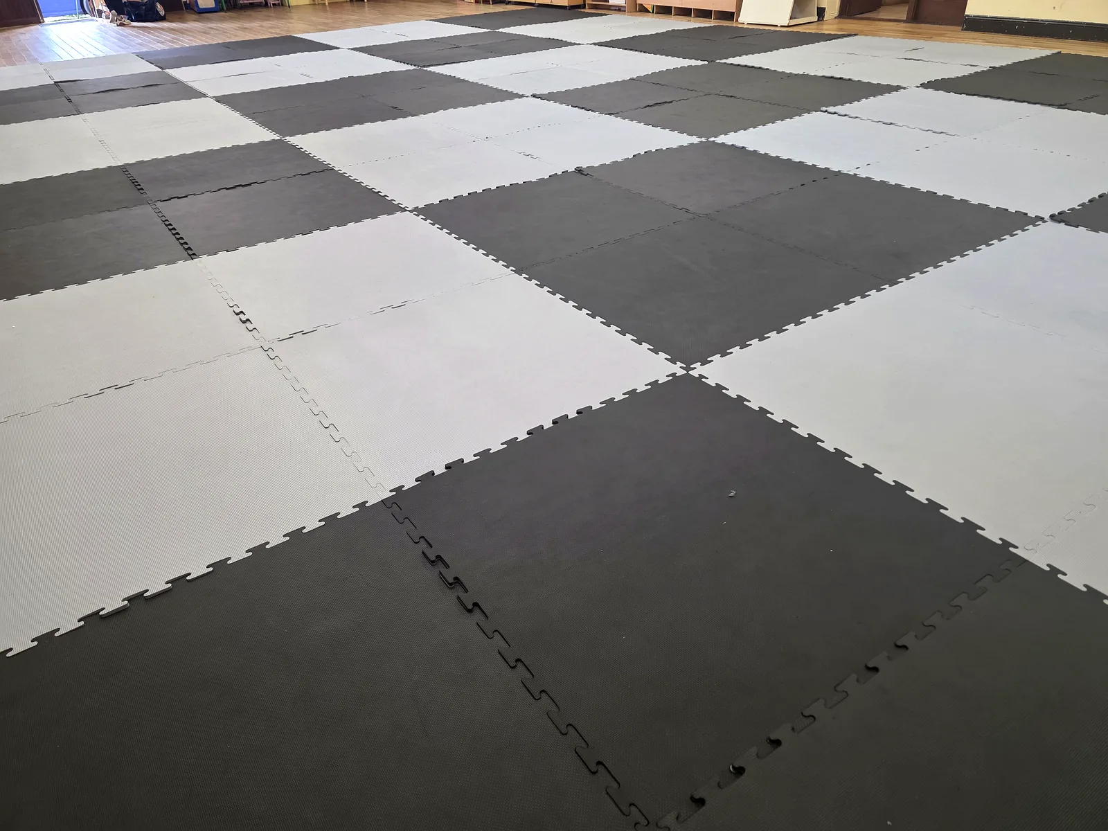 Full matted training floor at the Riverchapel Taekwon-Do venue, set out in a grey and black chequer pattern